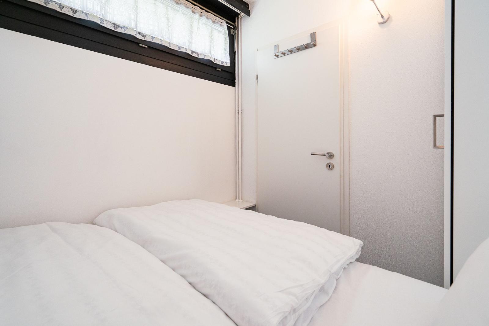 Schlafzimmer mit weißem Bett, Fenster und Tür