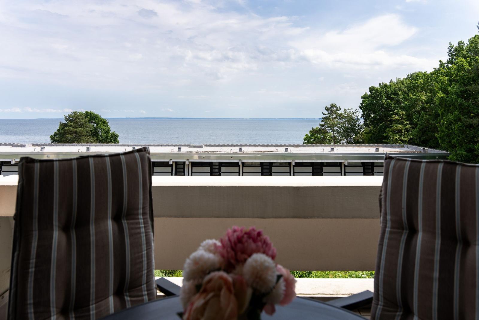 Balkon mit Sitzgelegenheiten und Blick aufs Wasser und Bäume