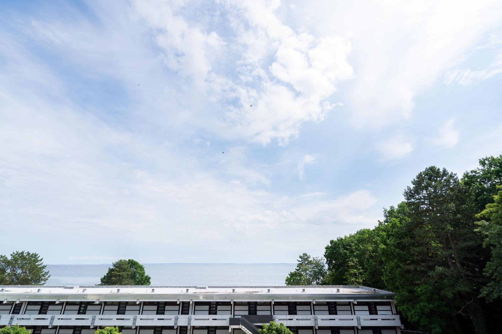 Haus mit Blick auf See und Himmel mit Wolken und Bäumen.