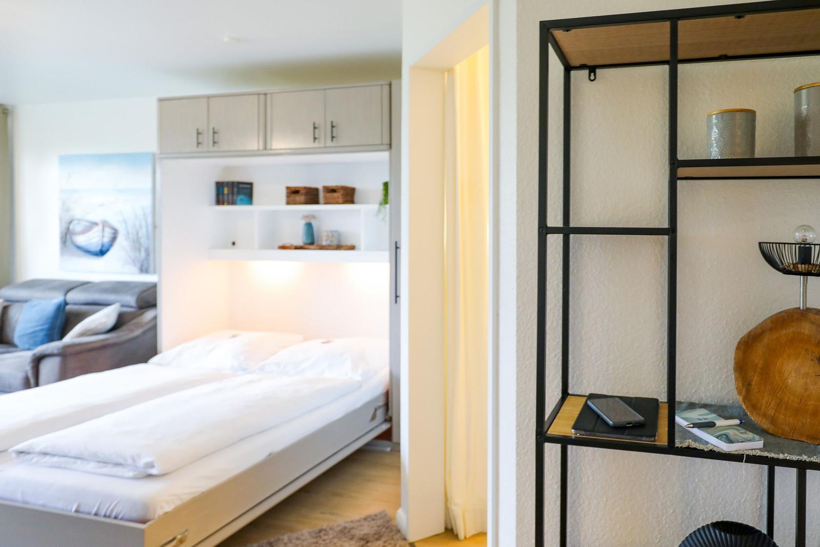 Schlafzimmer mit Bett und Küchenzeile im Hintergrund