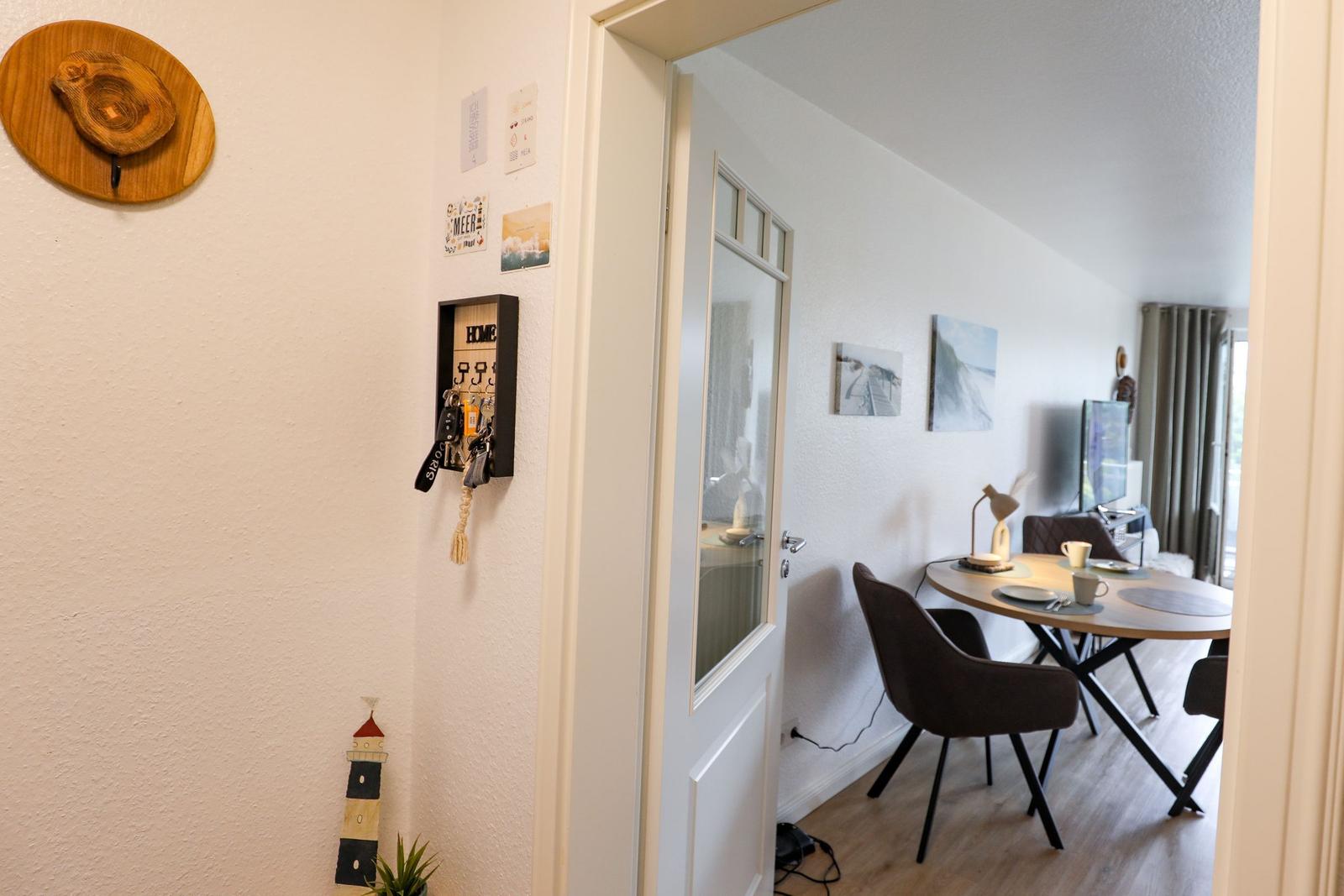 Eingangsbereich mit Schlüsselhalter und Blick in Esszimmer mit Tisch und Stühlen.