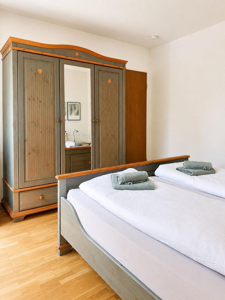 Schlafzimmer mit Doppelbett, Holzmöbel und Spiegeltüren im Schrank.