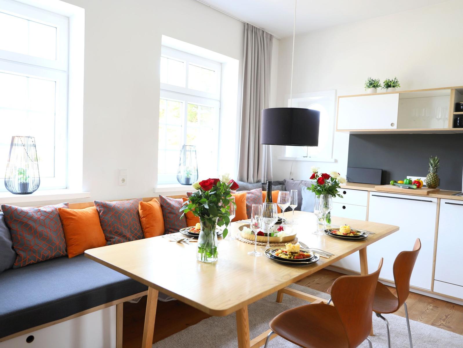Essbereich mit Holztisch, Sitzbank und Küchenzeile im Hintergrund.