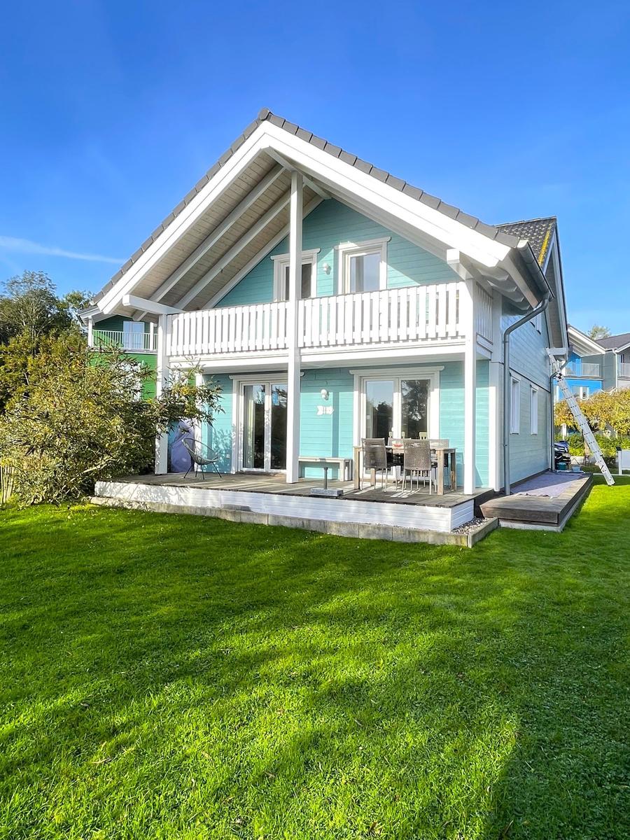 Ein zweistöckiges Haus mit Balkon und Terrasse auf grünem Grundstück.