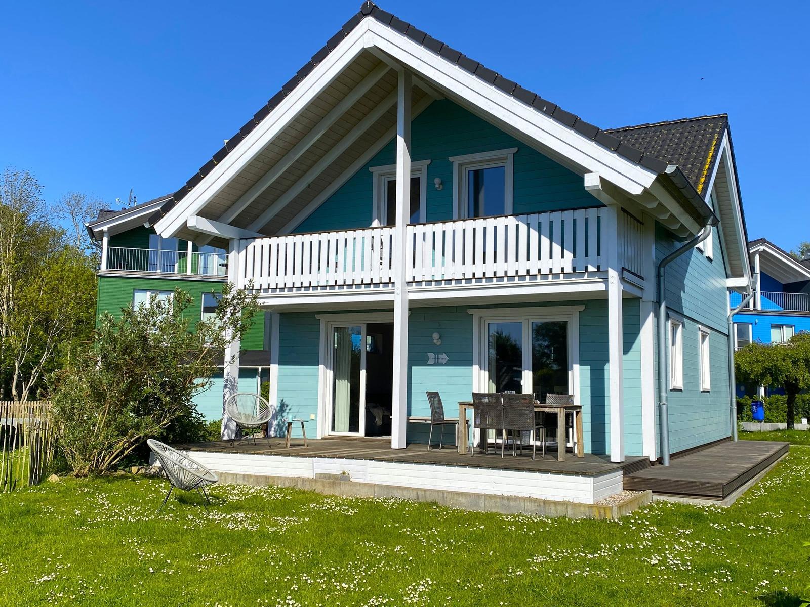 Ein zweistöckiges Haus mit Balkon und Terrasse im Freien.