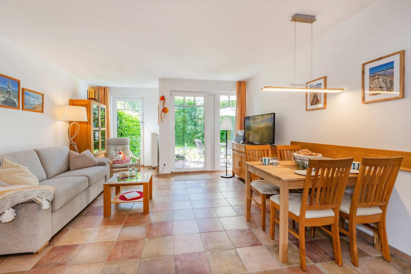 Wohn- und Essbereich mit Holztisch, Sofa und Glastüren zum Garten.