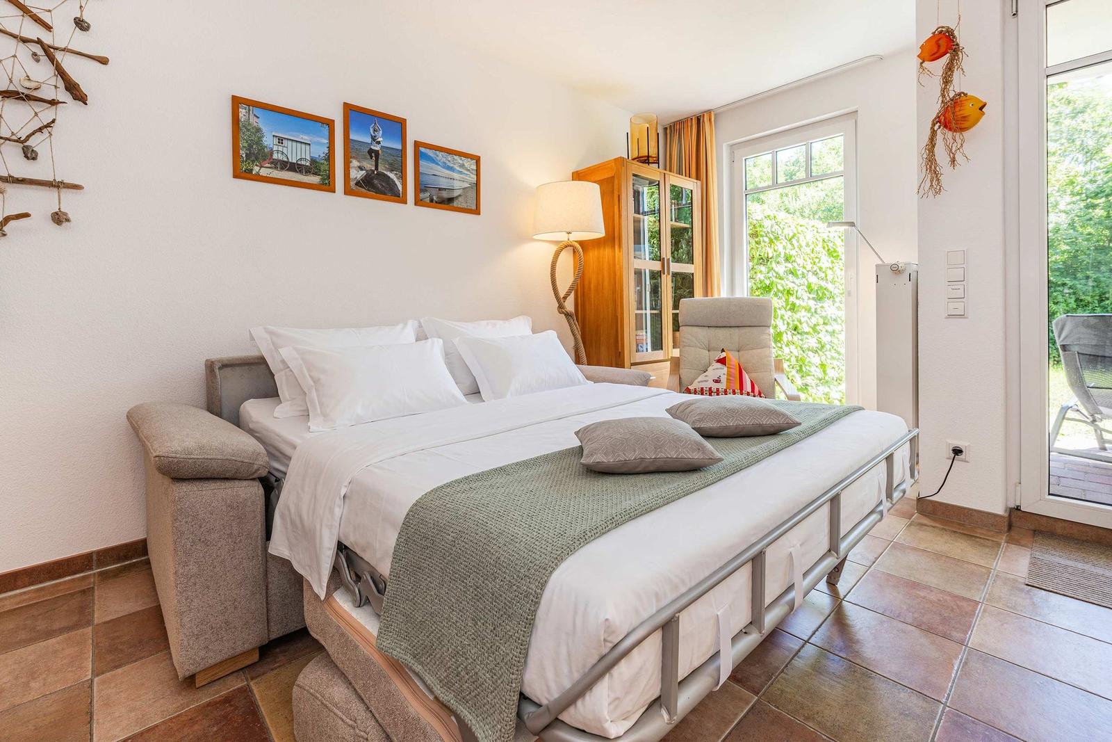 Schlafzimmer mit Doppelbett, Fenster und Tür zum Garten.