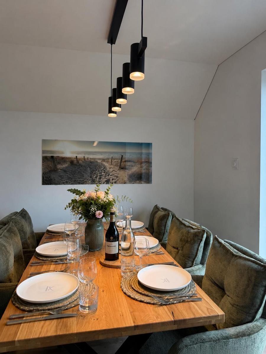 Esszimmer mit Holztisch, Stühlen und Wandbild. Hängelampe und Blumenvase.