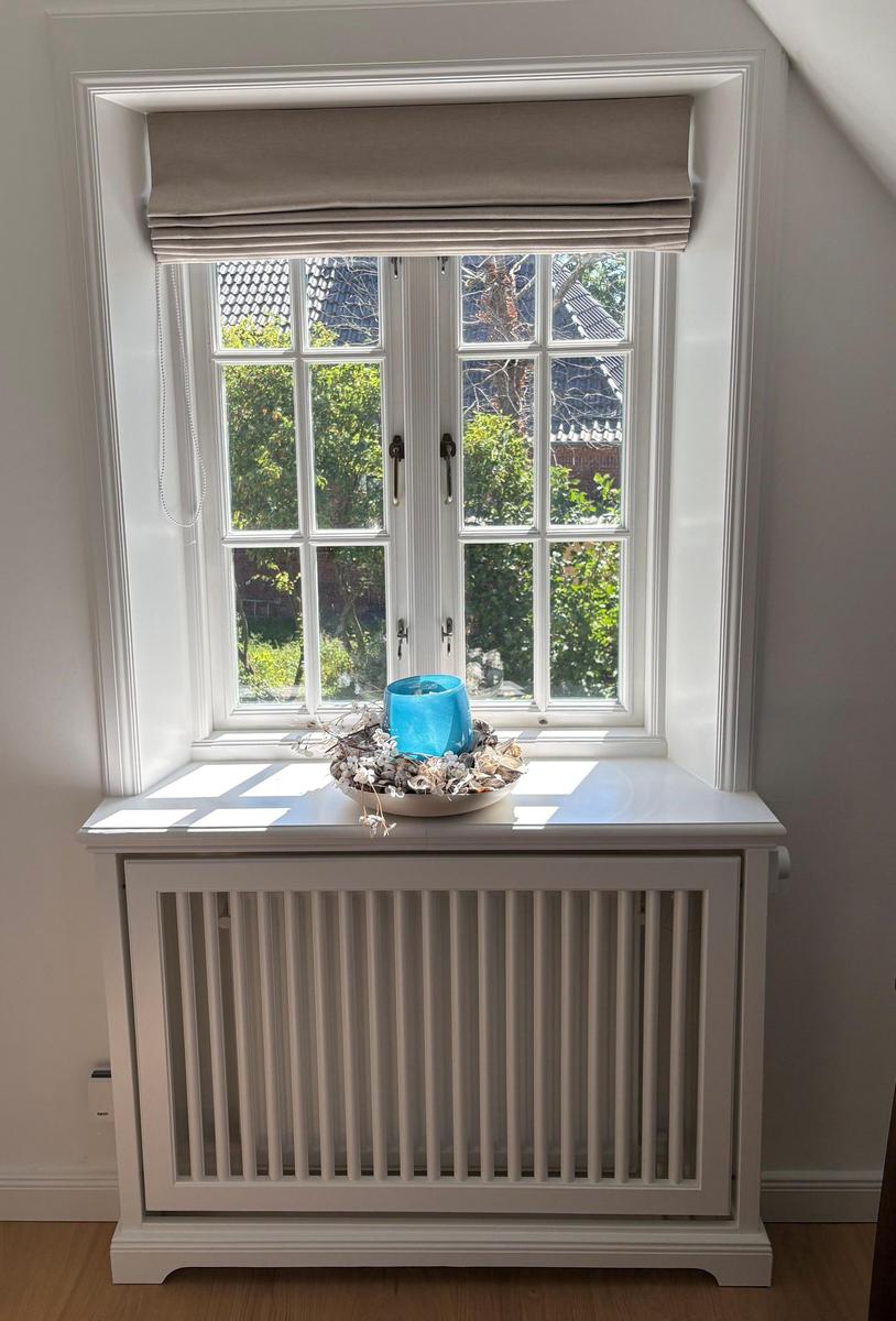 Ein Fenster mit Rollladen und einem Schale mit Muscheln auf dem Sims.
