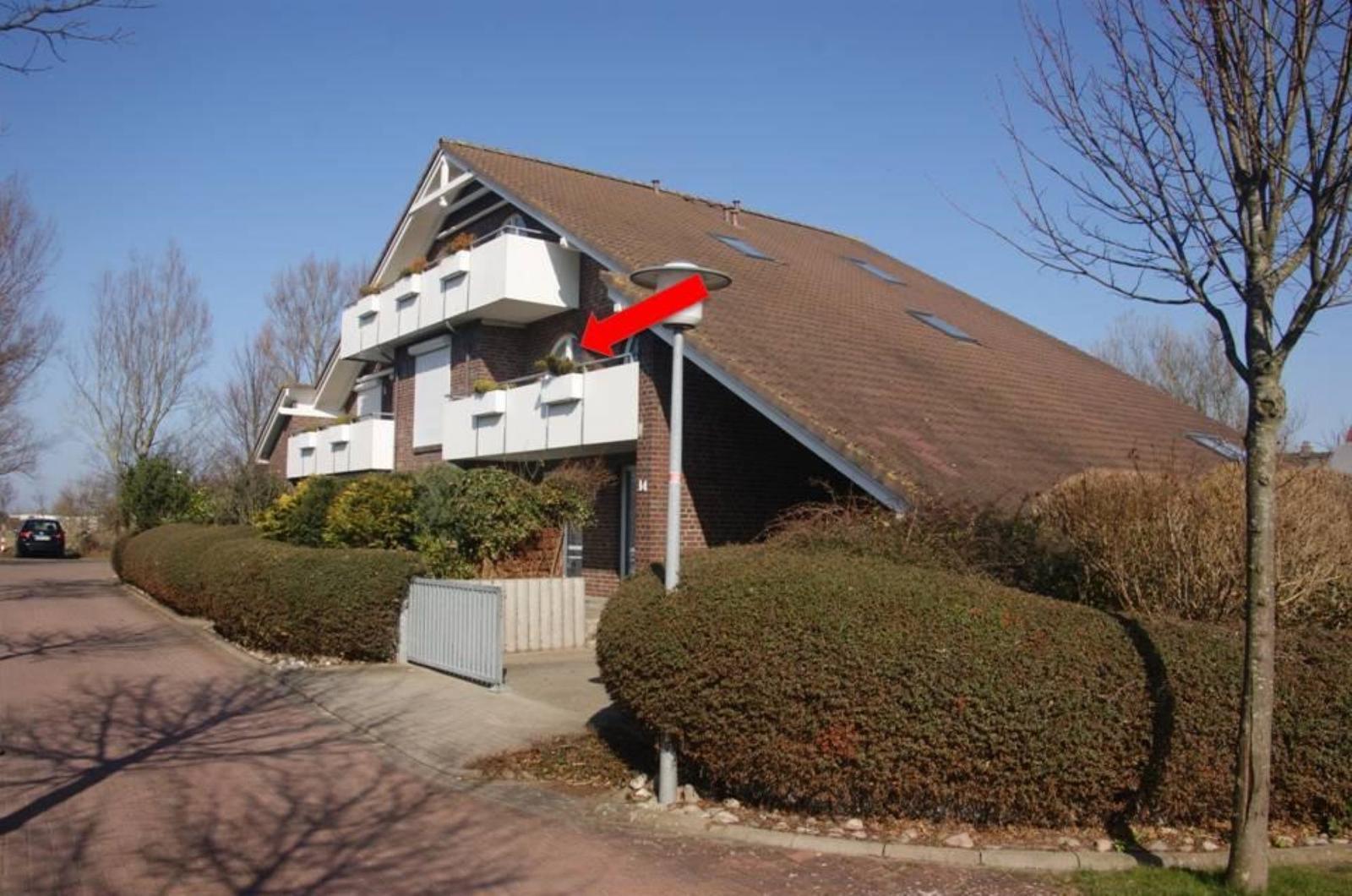 Modernes Mehrfamilienhaus mit Balkonen und Dachfenstern. Grünflächen und Gehweg sind gepflegt.