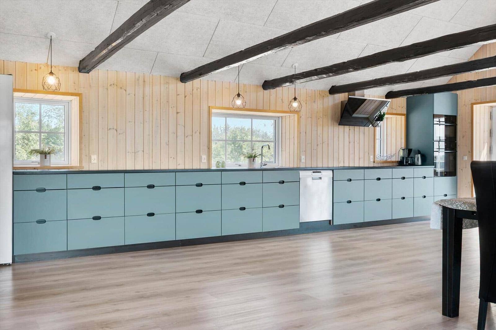Küche mit hellblauen Schränken, Holzwänden und schwarzen Balken an der Decke.