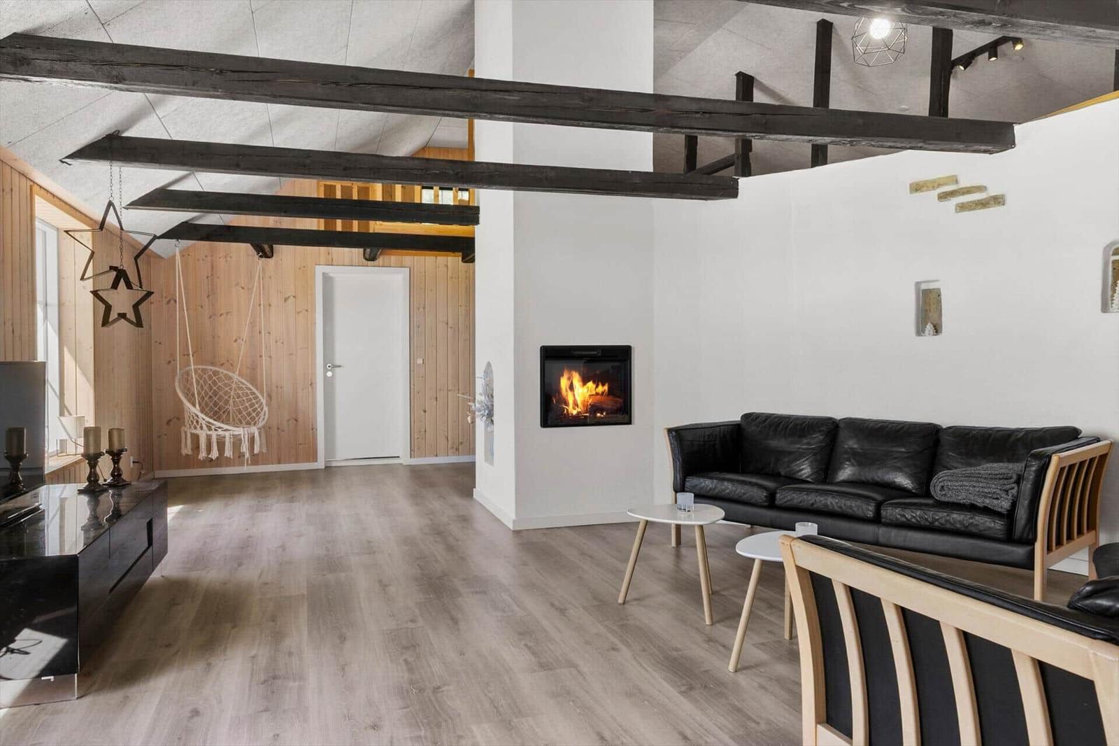 Wohnzimmer mit Kamin, Sofa und Holzbalken an der Decke.