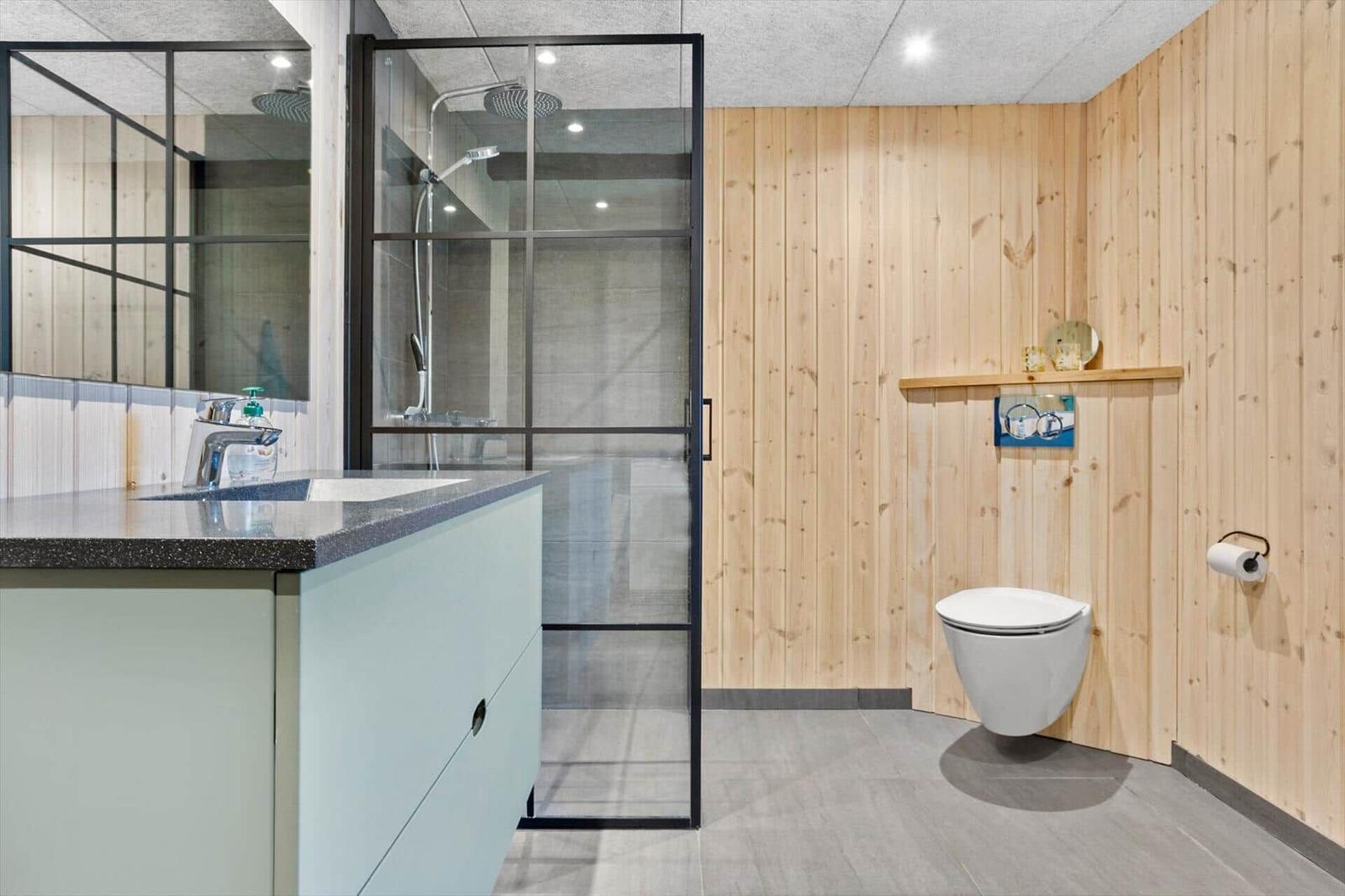 Bad mit Dusche, Waschbecken und Toilette an Holzwand