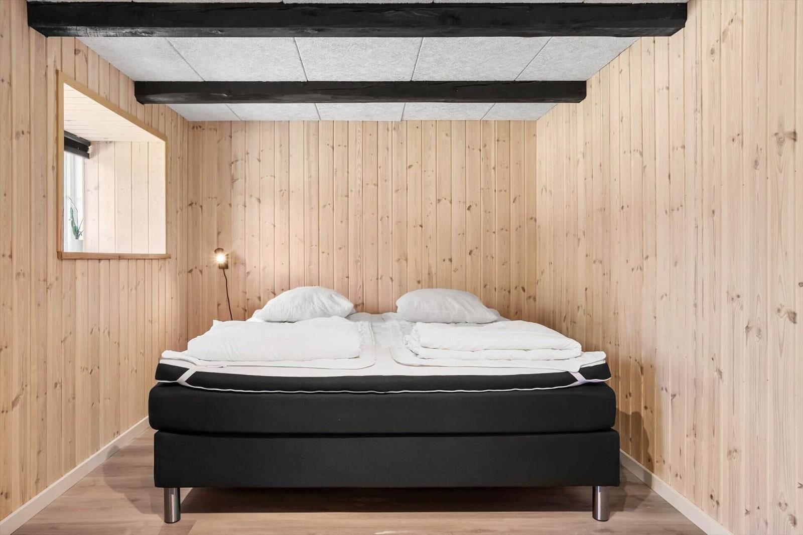 Schlafzimmer mit Holzwänden, Bett und Spiegel