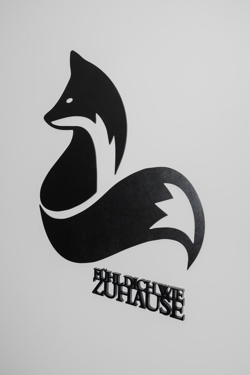 Schwarzes Fuchs-Logo mit Text FÜHL DICH WIE ZUHAUSE.
