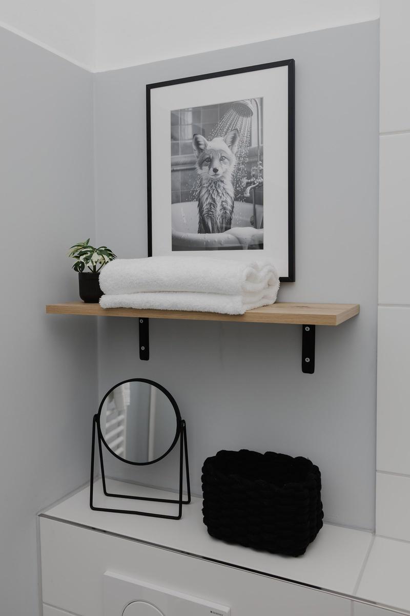 Badezimmer mit Holzregal, Badetuch, Pflanze und Bild eines Fuchses.