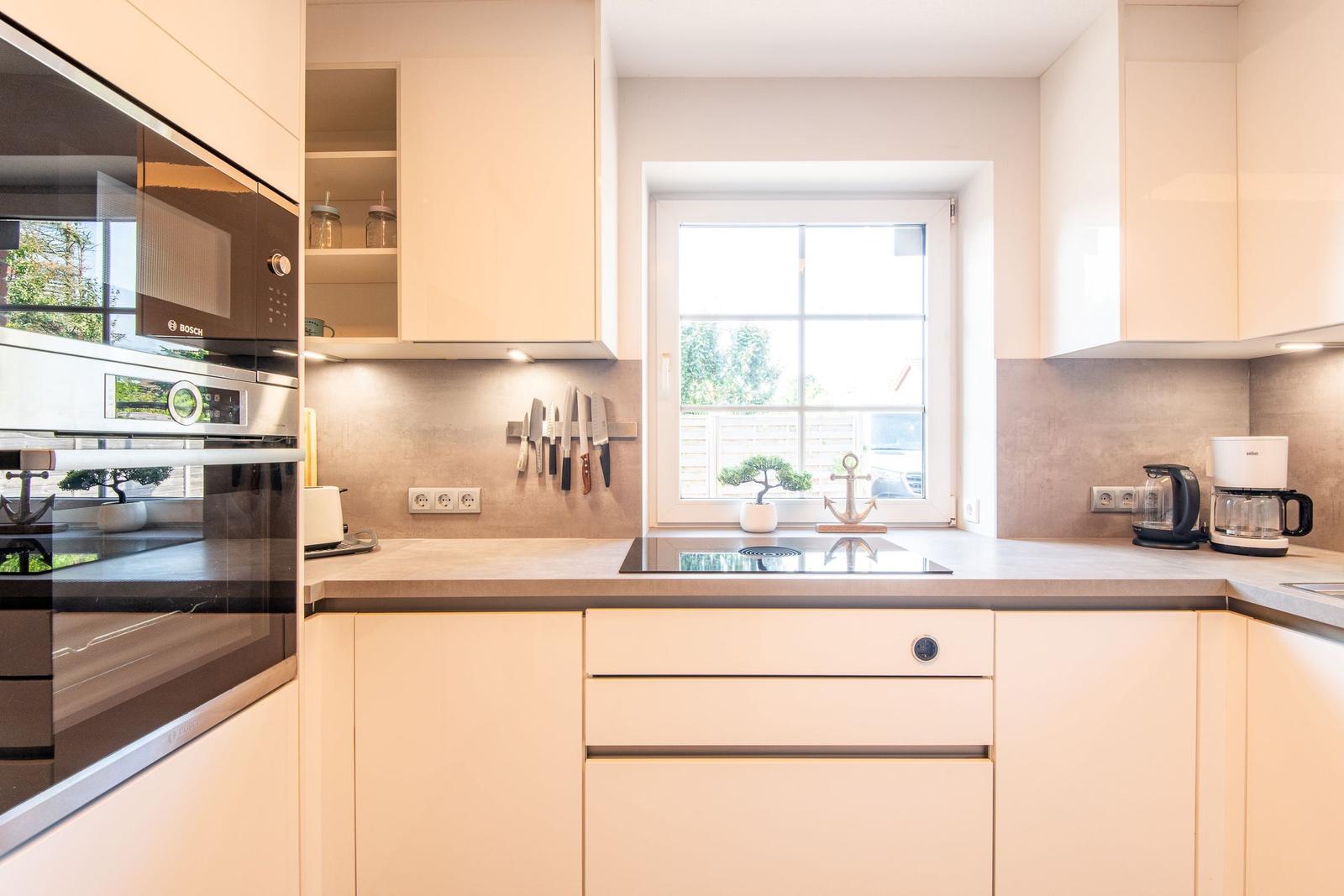 Moderne Küche mit Fenster, Arbeitsfläche und Einbauküchengeräten.