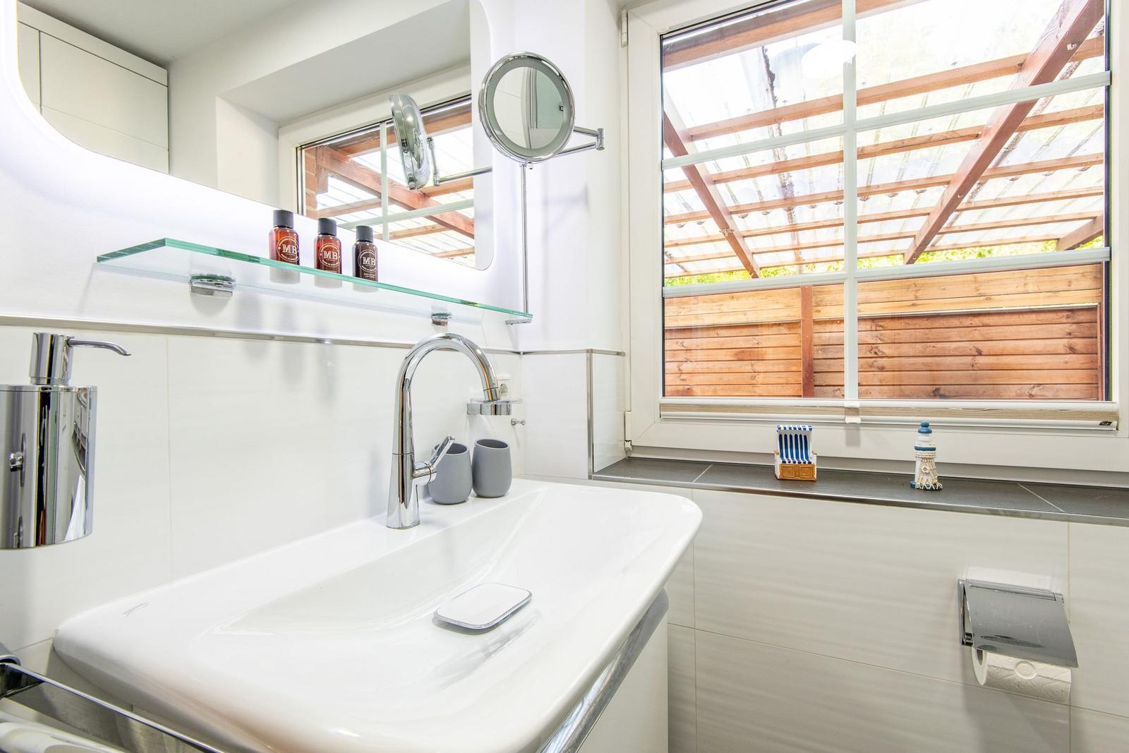 Bad mit Waschbecken, Spiegel und Fenster zum Garten