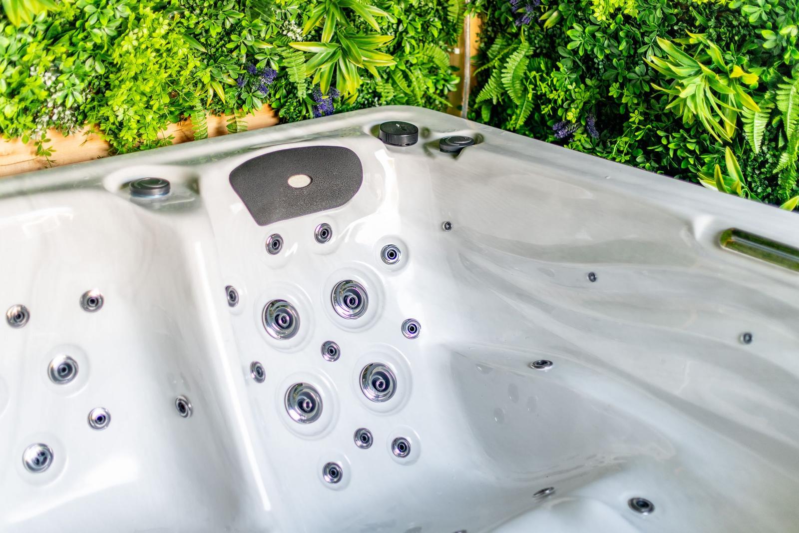Whirlpool mit mehreren Düsen vor grüner Pflanzenwand