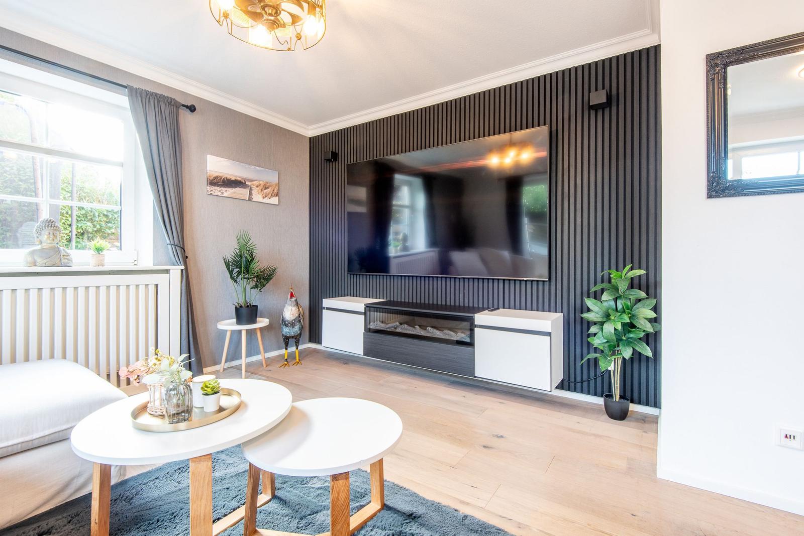 Wohnzimmer mit Fernseher, Sitzgelegenheit und Pflanzen.