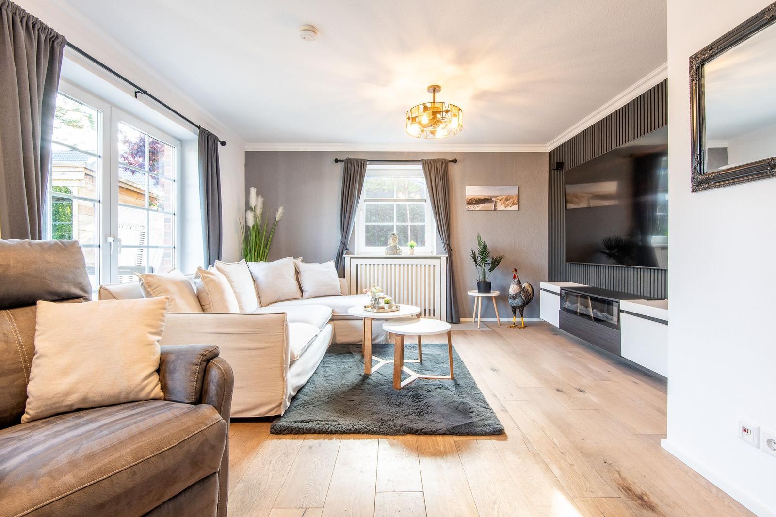 Wohnzimmer mit Sofa, Teppich und Fernseher an der Wand.
