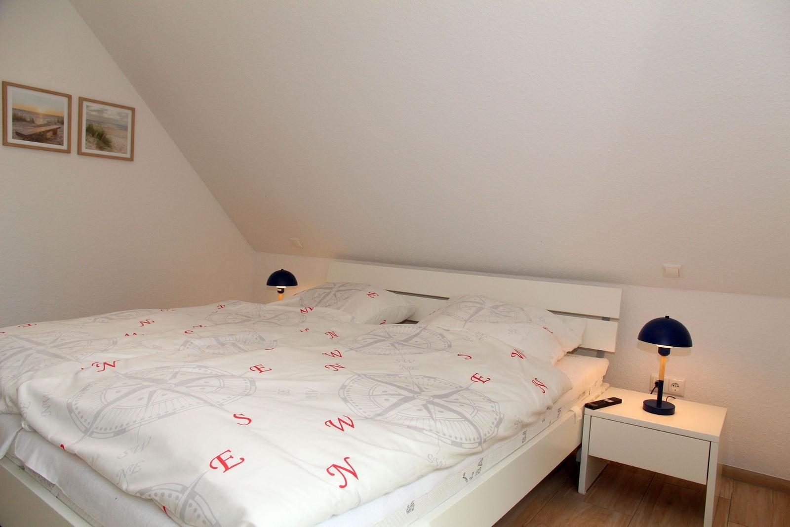 Schlafzimmer mit Doppelbett, zwei Nachttischen und gemalten Wandbildern.