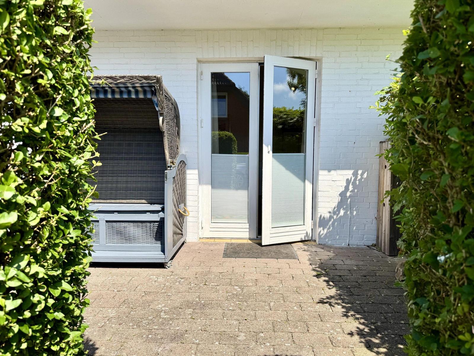 Haus mit Gartentür und Liegestuhl im Garten
