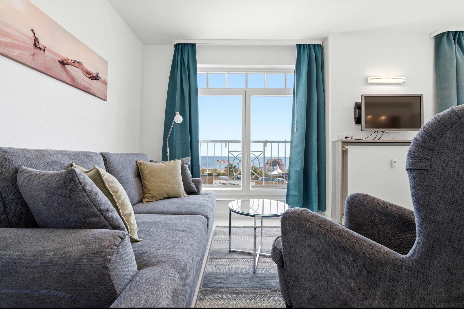 Wohnzimmer mit Sofa, Sessel und Blick auf die Terrasse.