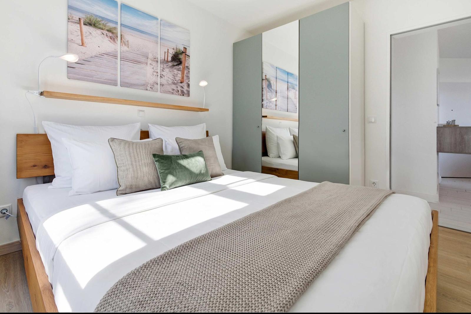 Schlafzimmer mit Bett, Wandbild und Kleiderschrank. Holzfußboden und Licht.