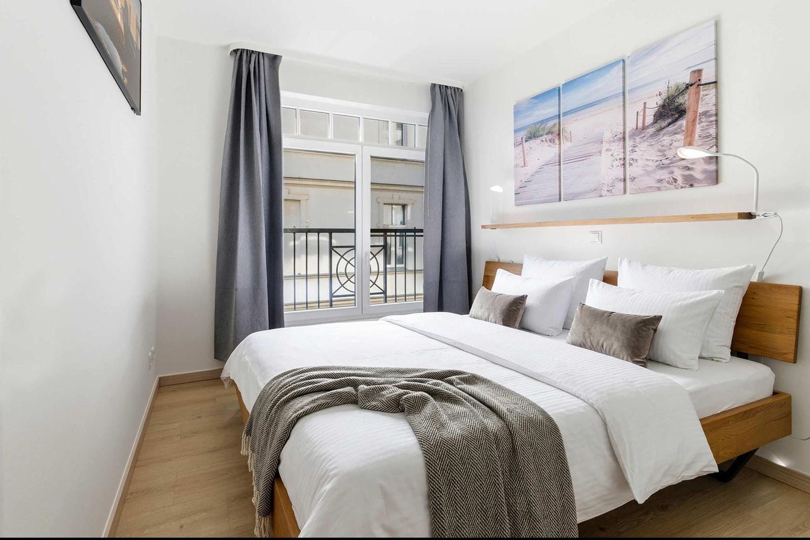 Schlafzimmer mit Bett, Fenster und Wandbildern.