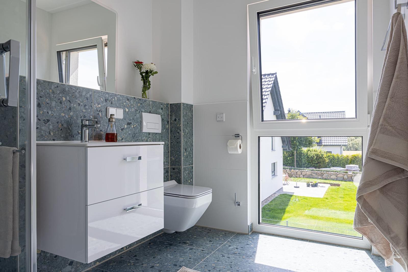 Badezimmer mit Waschbecken, Toilette und Fenster zum Garten.
