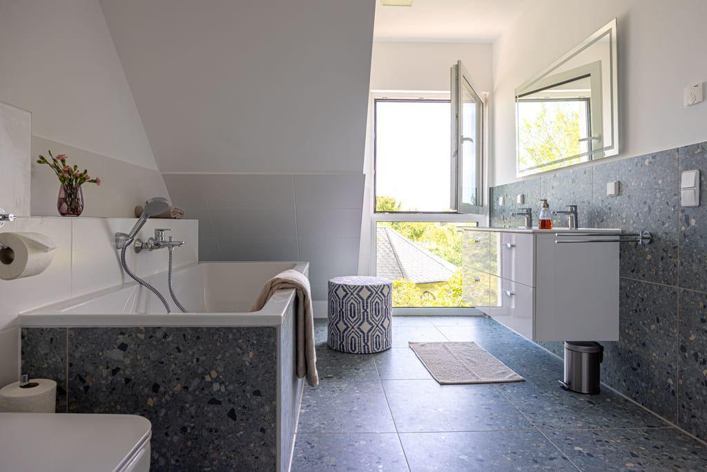 Badezimmer mit Badewanne, Waschbecken und Fenster mit Blick nach draußen.