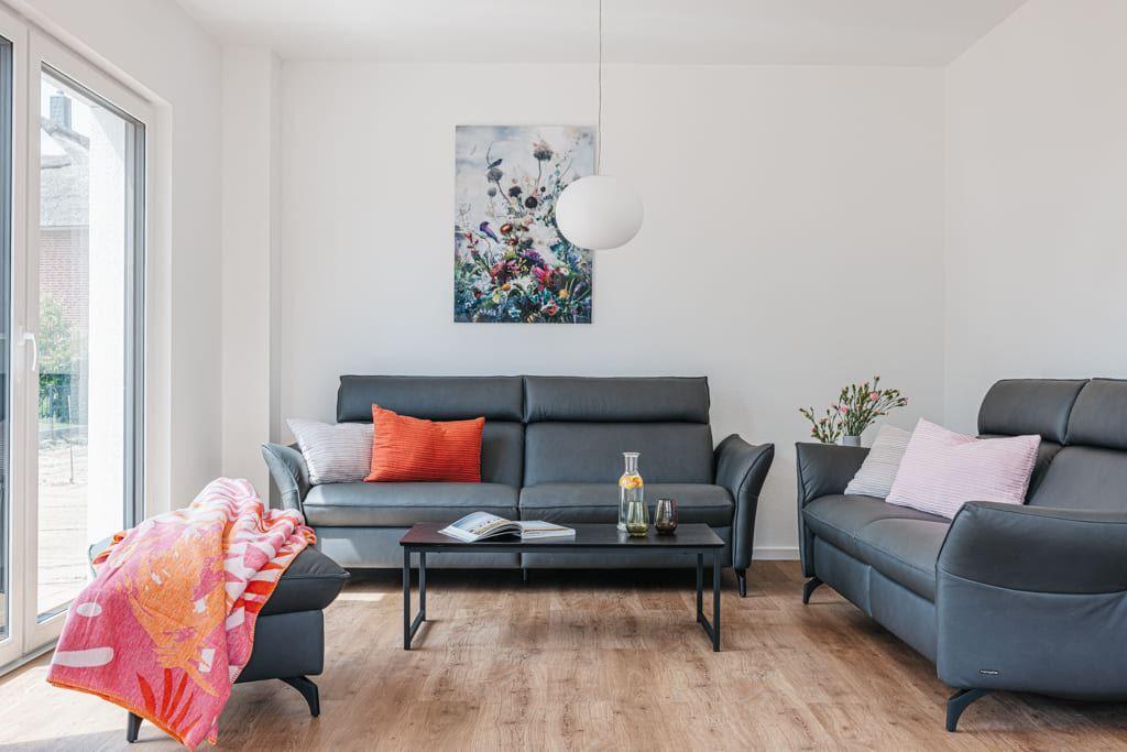 Wohnzimmer mit zwei Sofas, Tisch und Fenster. Wandbild und Hängelampe.