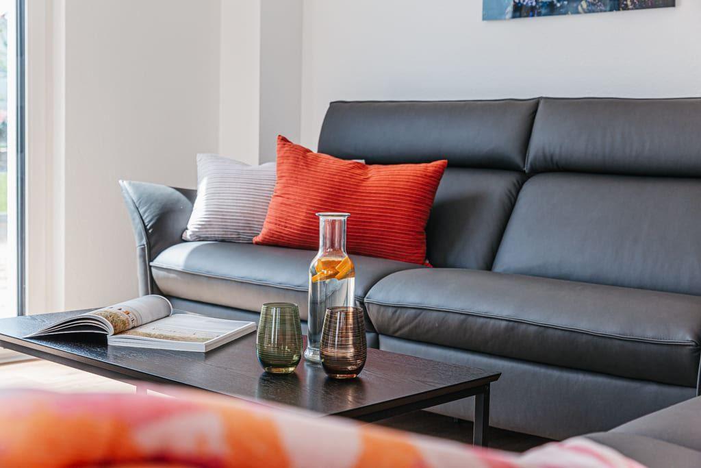 Ein schwarzes Sofa mit Kissen und einem Tisch mit Gläsern und einer Flasche.