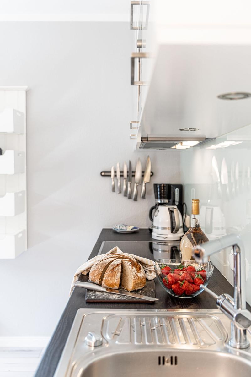 Küchenzeile mit Brot, Erdbeeren, Kaffeemaschine und Messerblock.