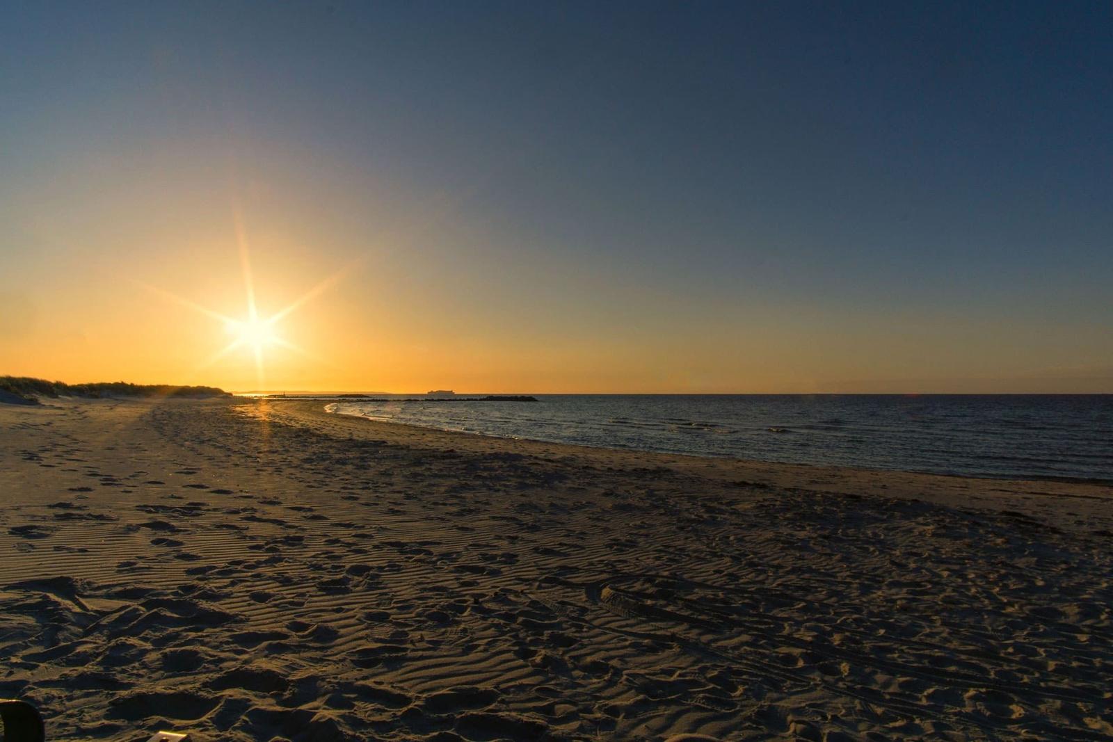Sonnenaufgang am Strand mit sanften Wellen und sandigem Ufer