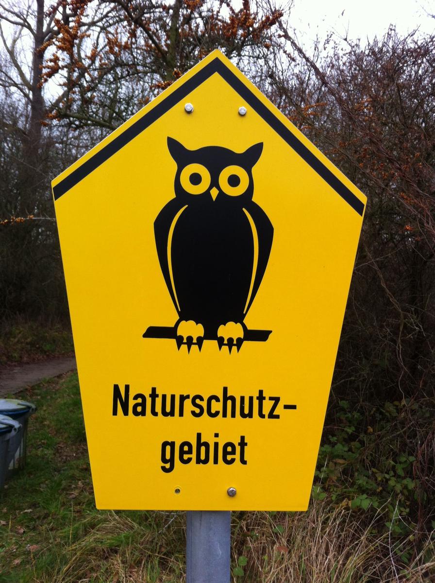 Schild weist auf Naturschutzgebiet hin mit Eule als Symbol