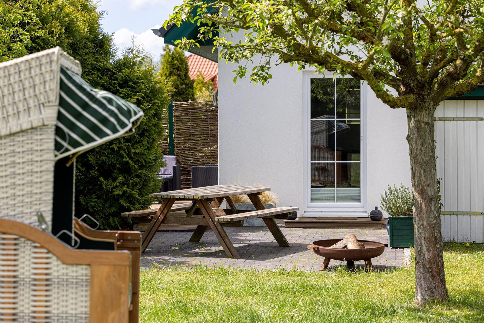 Hinterhof mit Picknicktisch, Grillplatz und Wicker-Sitzmöbel unter Baum.