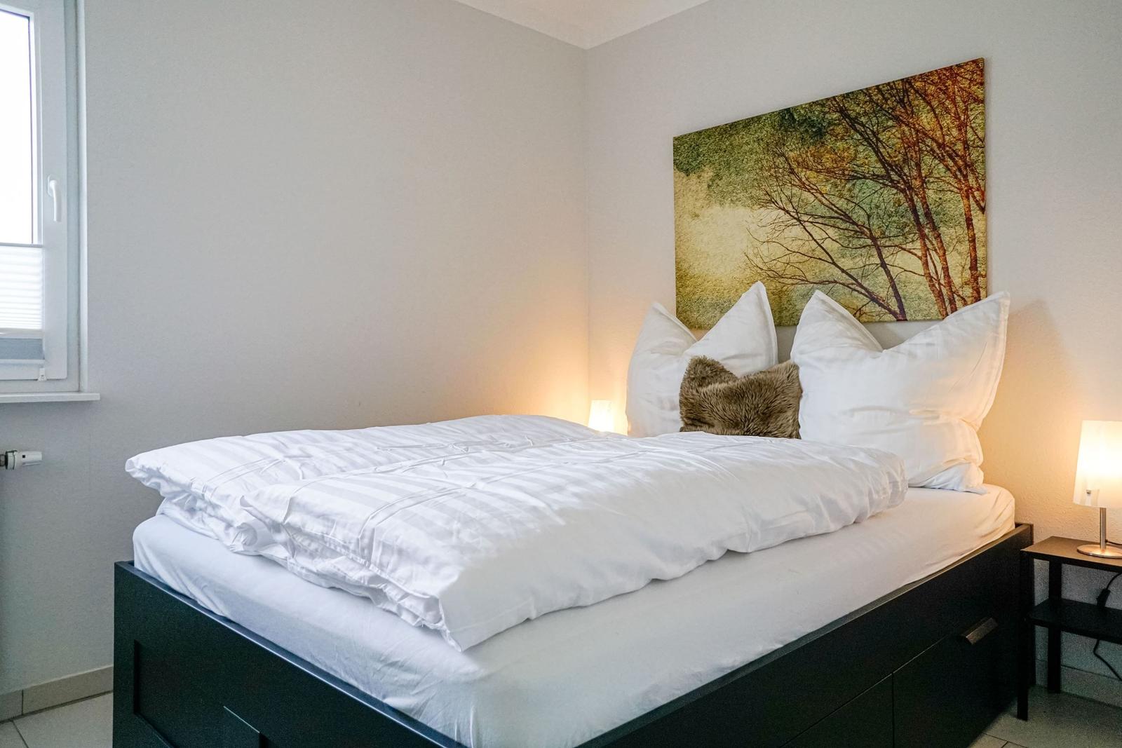 Schlafzimmer mit Bett, Wandbild und Nachttisch