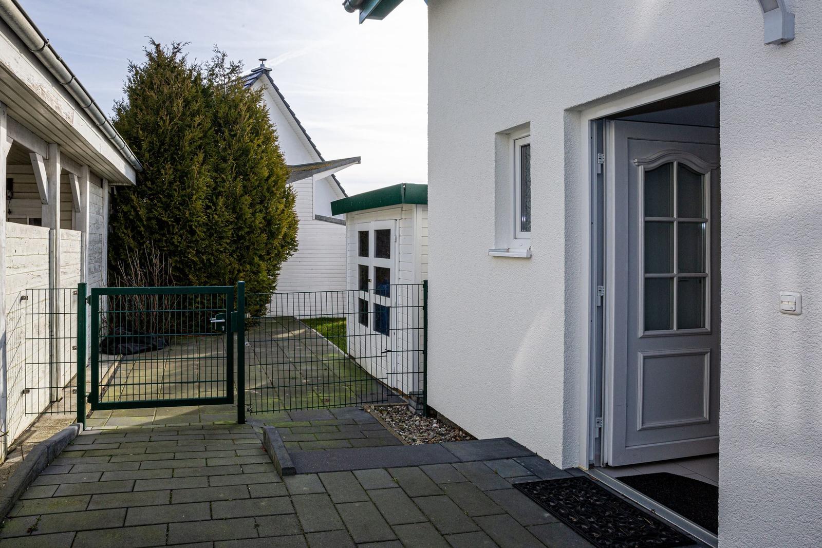 Eingangstür mit Gartentor und gepflastertem Weg zur Villa.