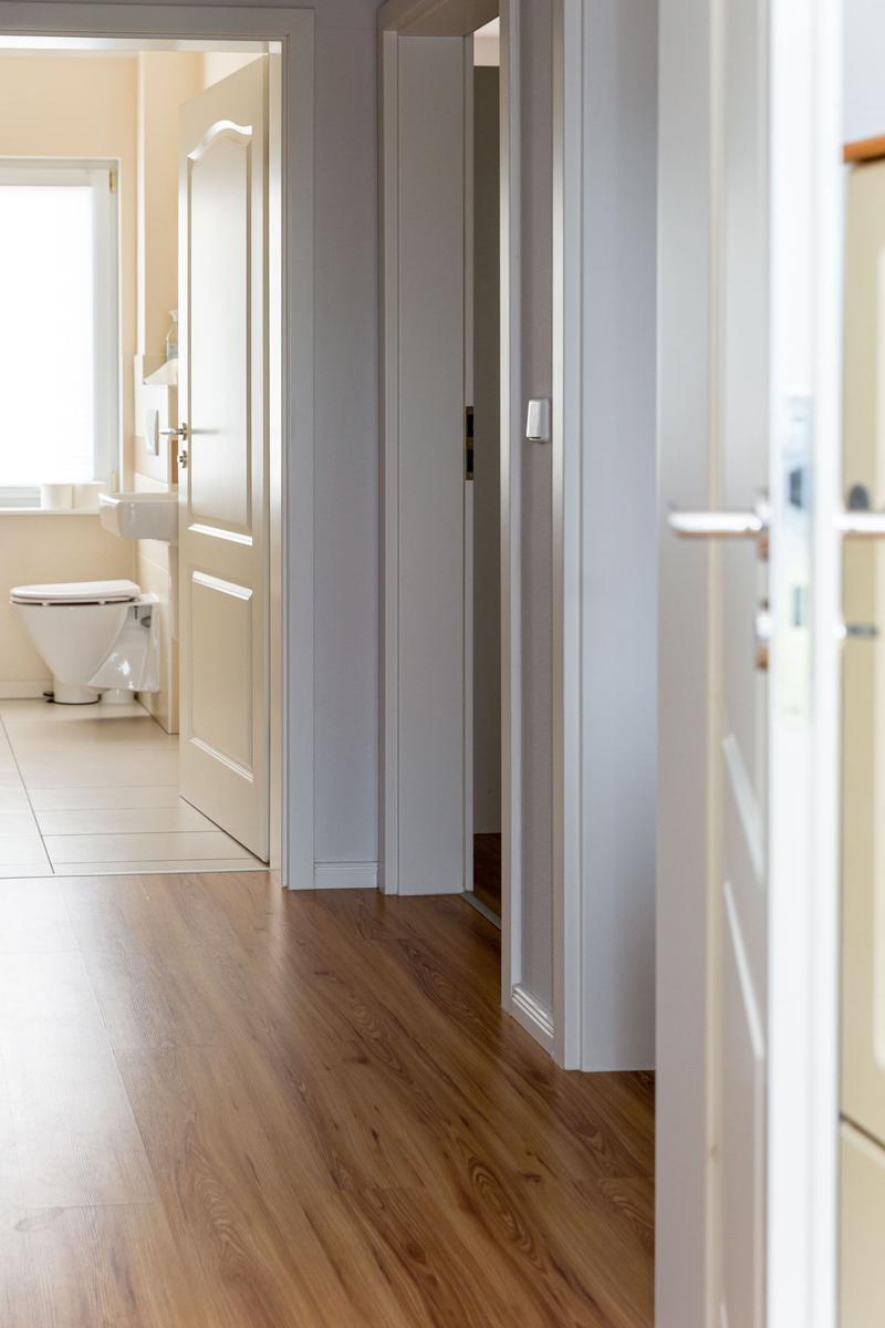 Flur mit Holzboden und Blick in Bad mit Toilette und Waschbecken