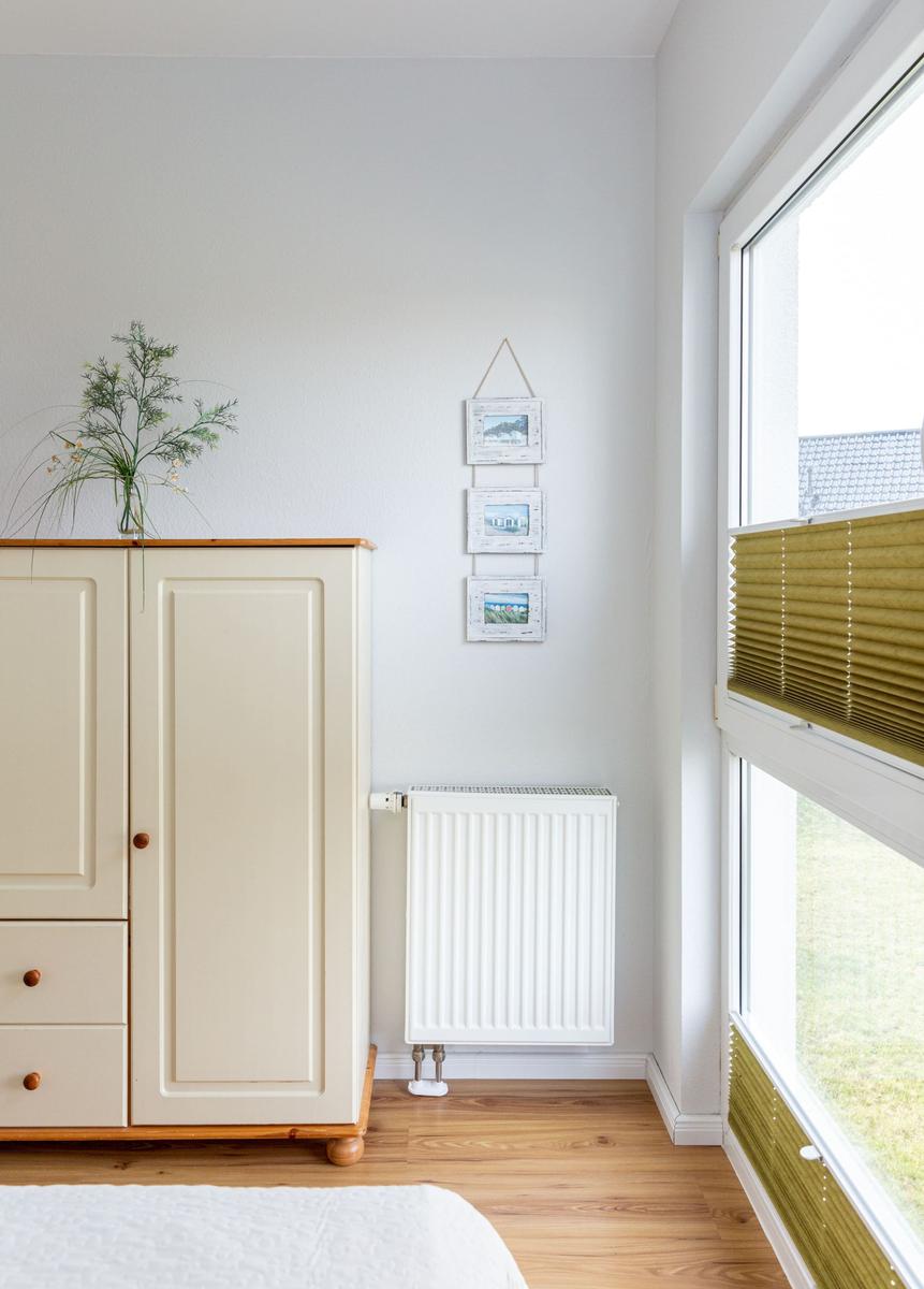 Schlafzimmer mit Kleiderschrank, Heizung und Fenster mit Jalousie.