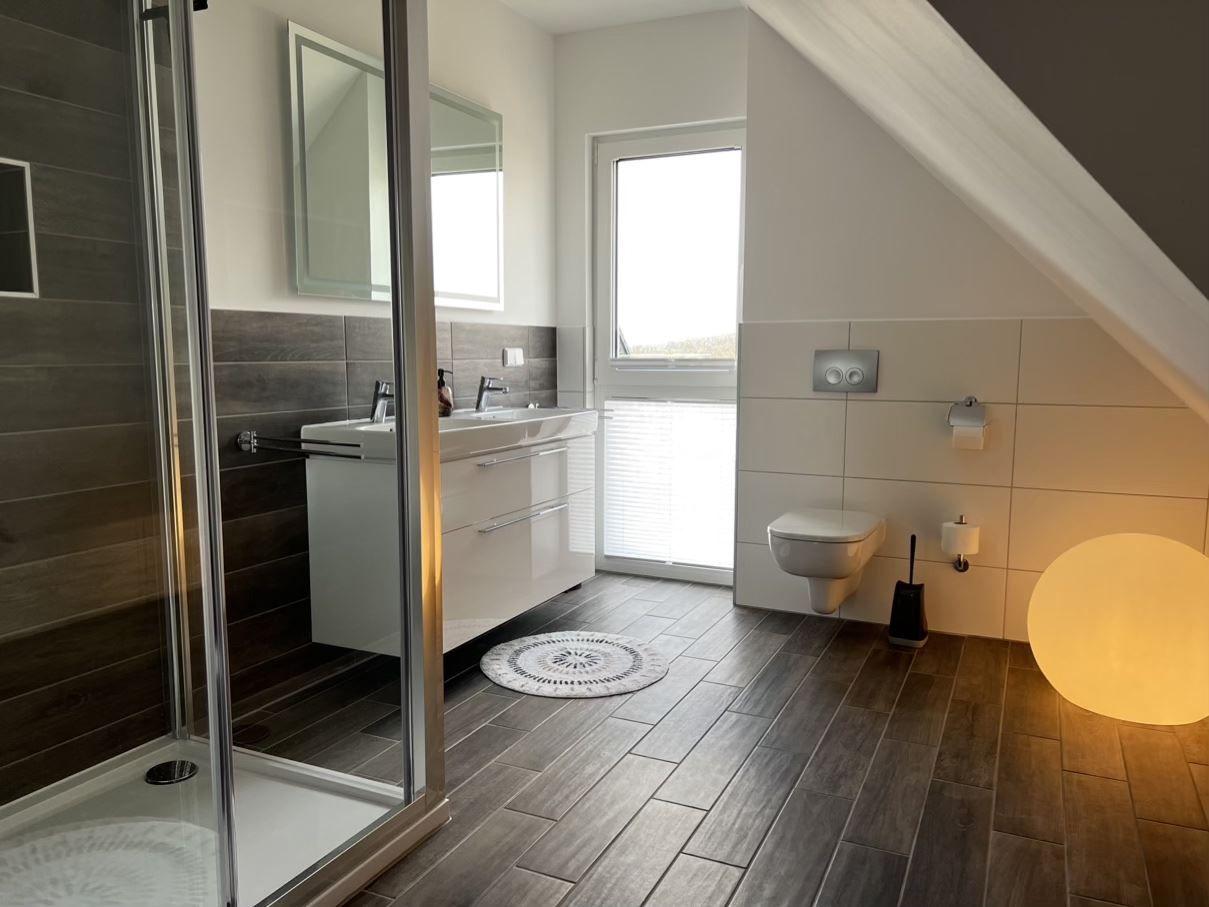 Badezimmer mit Dusche, Waschbecken und WC unter Dachschräge.