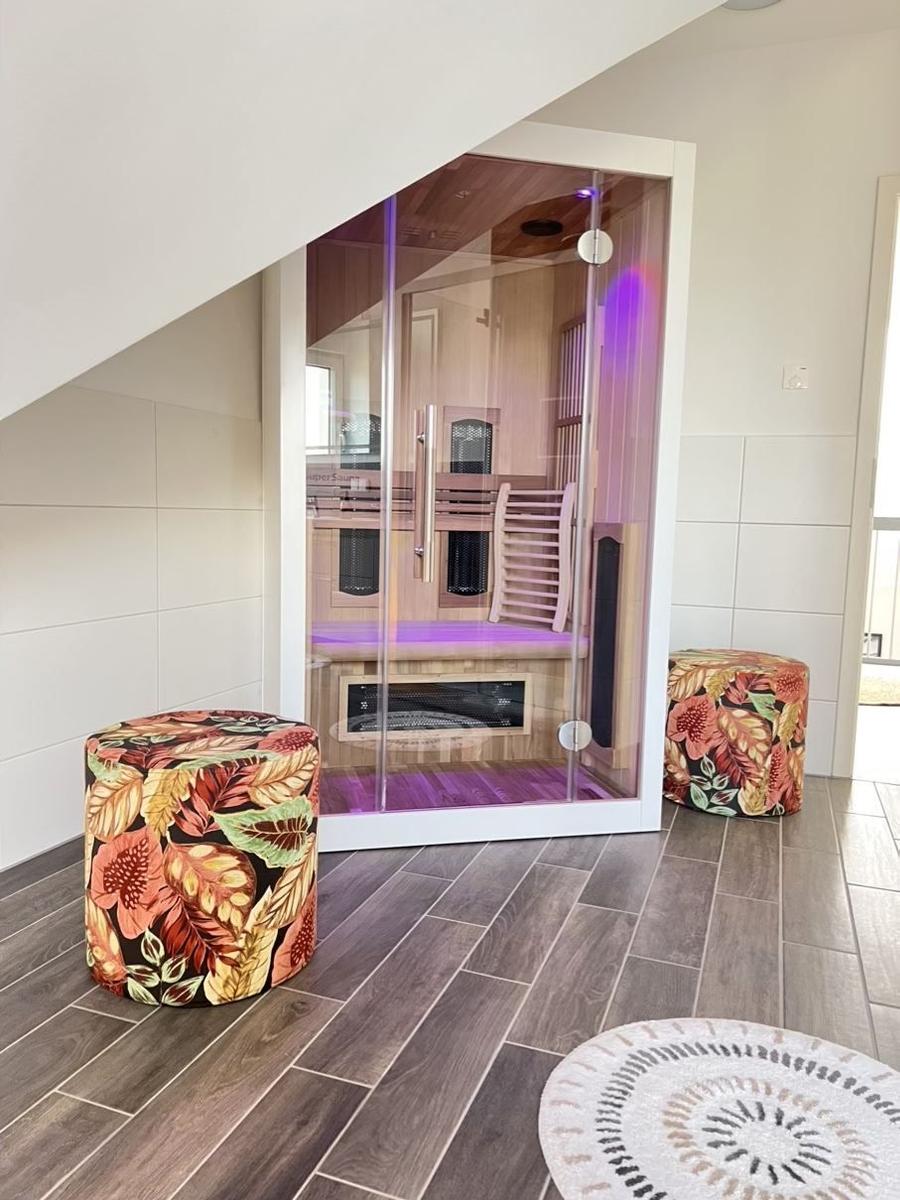 Sauna mit Glasfront und zwei floralen Sitzkissen auf Holzboden