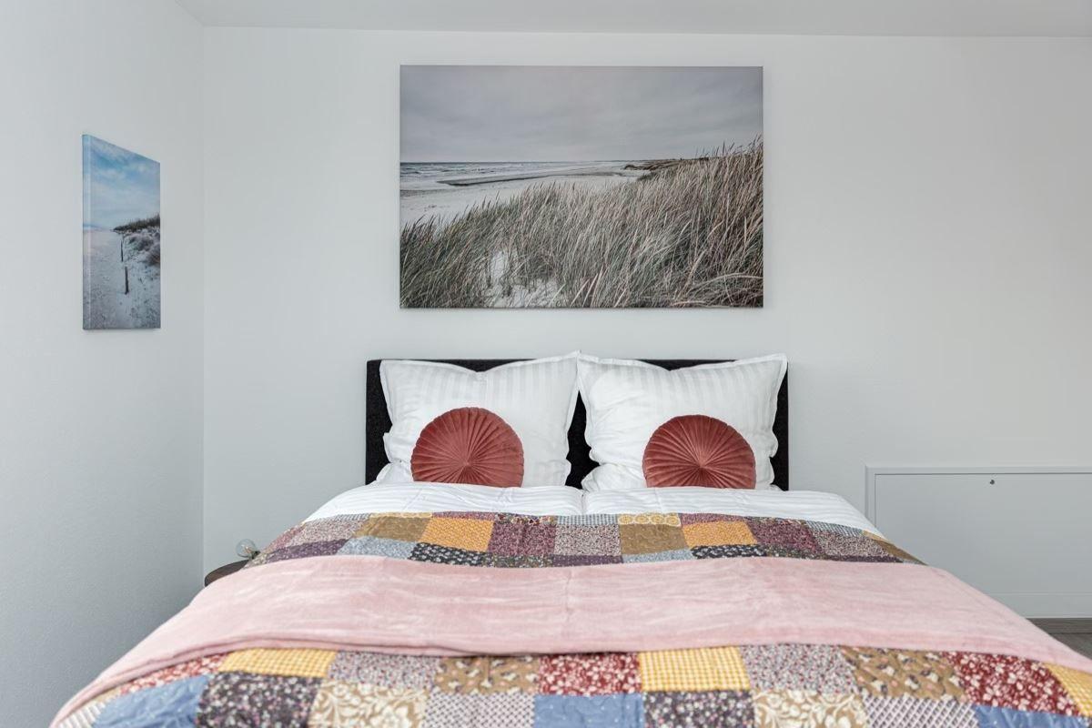 Schlafzimmer mit Bett, Decke und Wandbildern