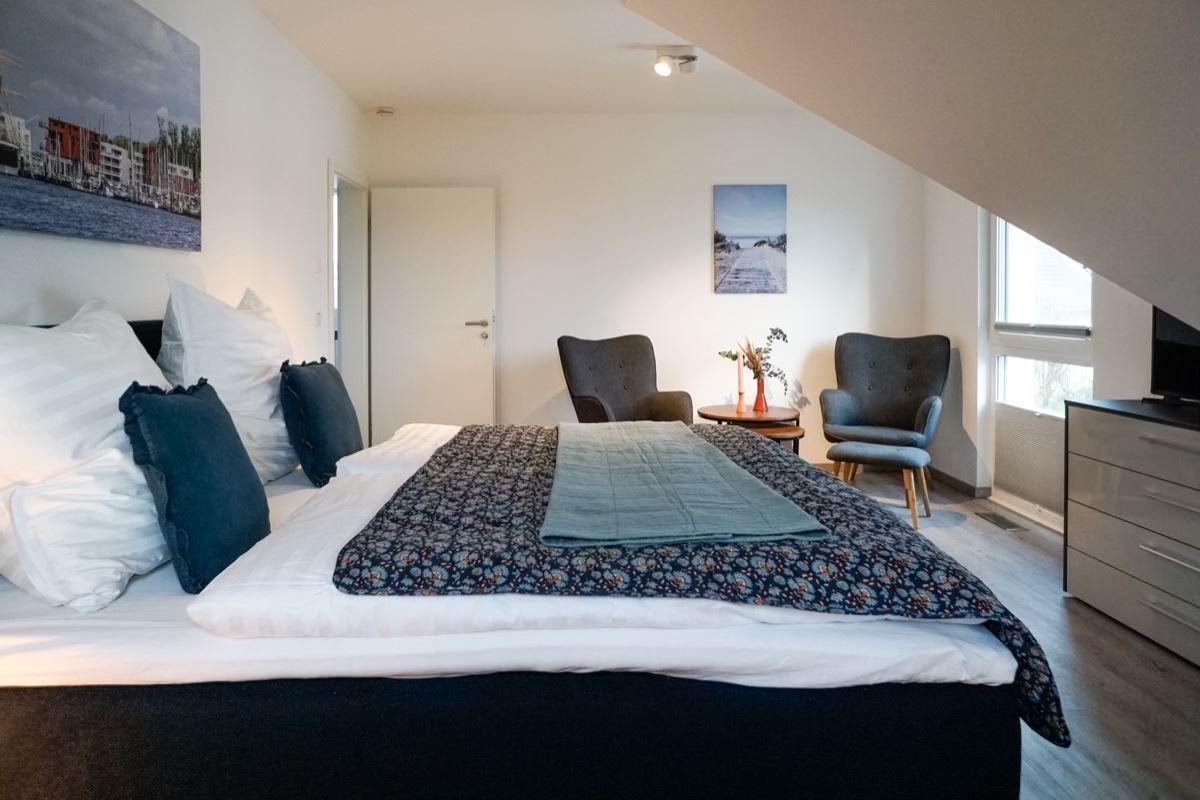 Schlafzimmer mit Bett, zwei Sesseln und Fenster unter Dachschräge.