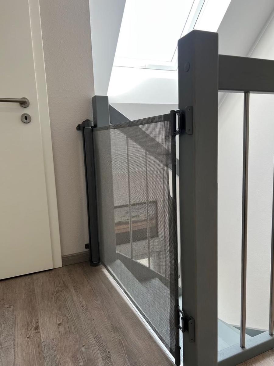Sicherheitsgitter an Treppenhaus mit Holzboden und Dachfenster.