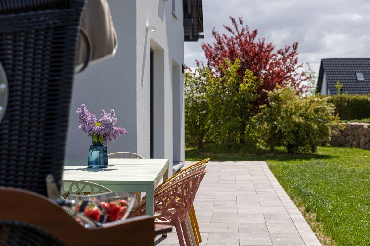 Terrasse mit Tisch, Stühlen und Blumen. Hintergrund: Garten und Haus.