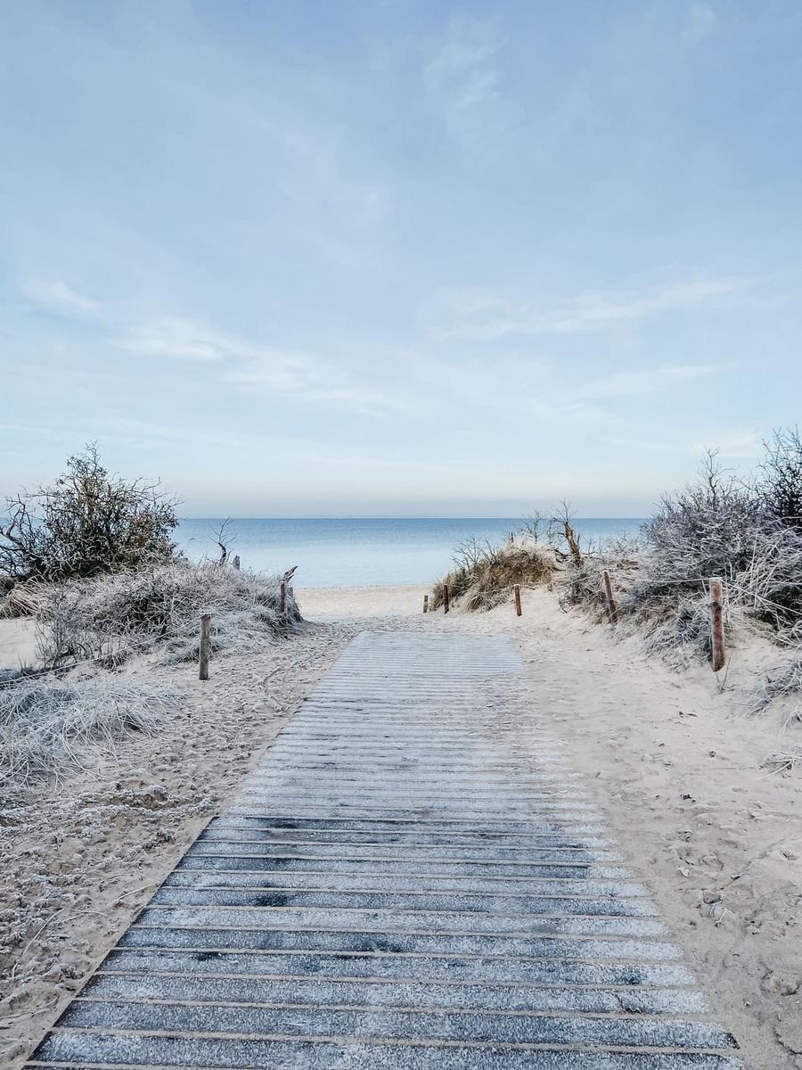 Holzweg führt durch Sanddünen zum Strand und Meer.