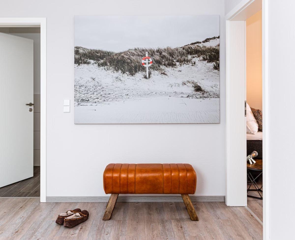 Ein brauner Ledersitzbank steht unter einem großen Wandbild mit Strandmotiv.